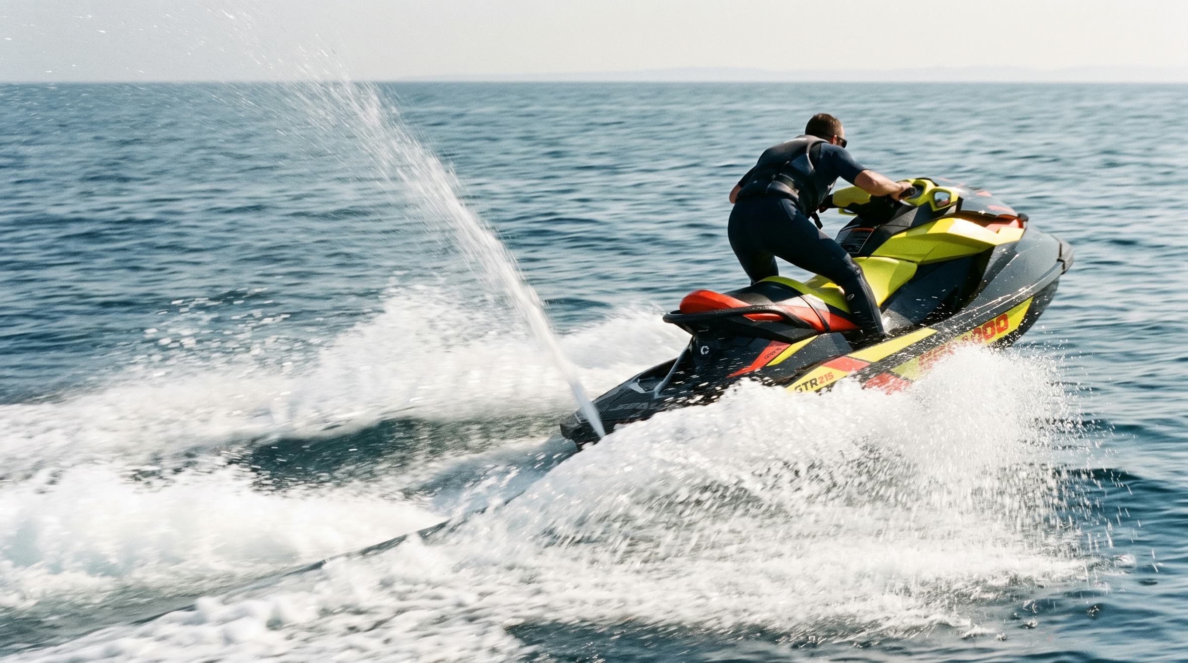 Vodní skútr Sea-Doo GTR 215 zrychluje pryč od kamery s velkou sprškou vody